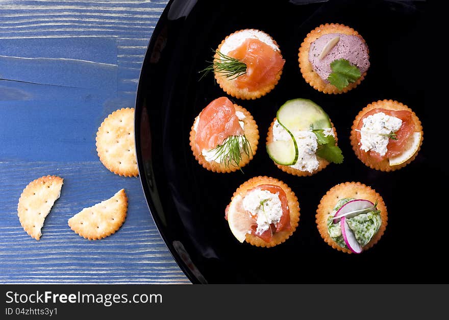 Light snack from various ingredients with soft cheese and herbs on crackers.