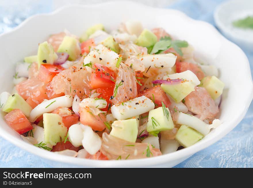 A bowl of salad with squid, avocado and grapefruit, closeup horizontal