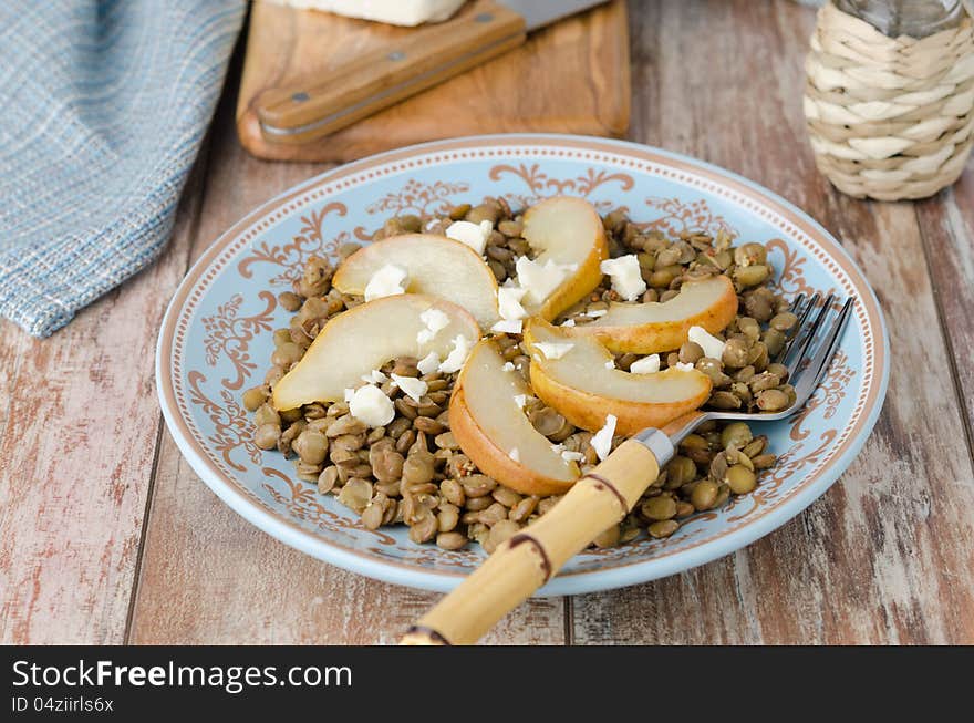 Lentil salad with caramelized pears and Roquefort cheese on a blue plate, horizontal