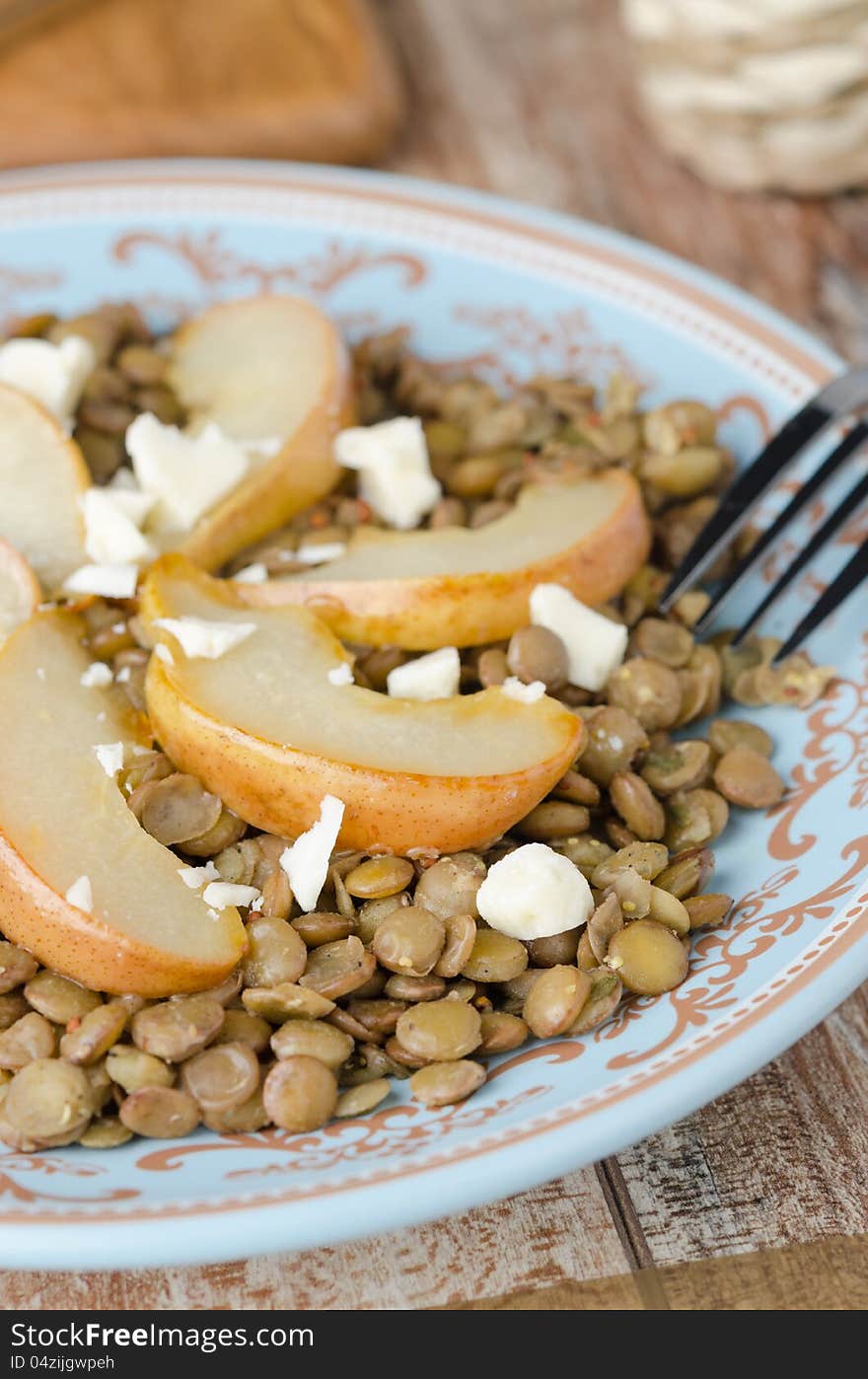 Lentil salad with caramelized pears and Roquefort cheese on a blue plate, closeup. Lentil salad with caramelized pears and Roquefort cheese on a blue plate, closeup