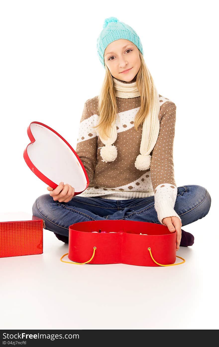 Girl in winter hat sitting with gift boxes