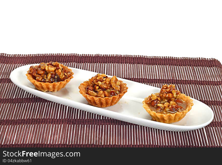 Walnut cakes in row on long white dish over brown mat