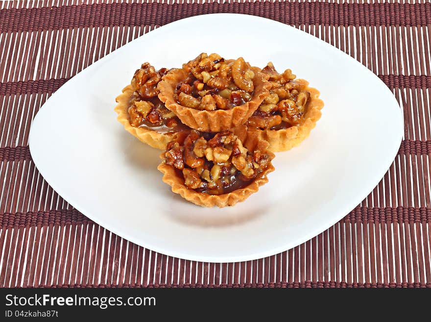 Walnut cakes in pyramid on white dish over brown mat