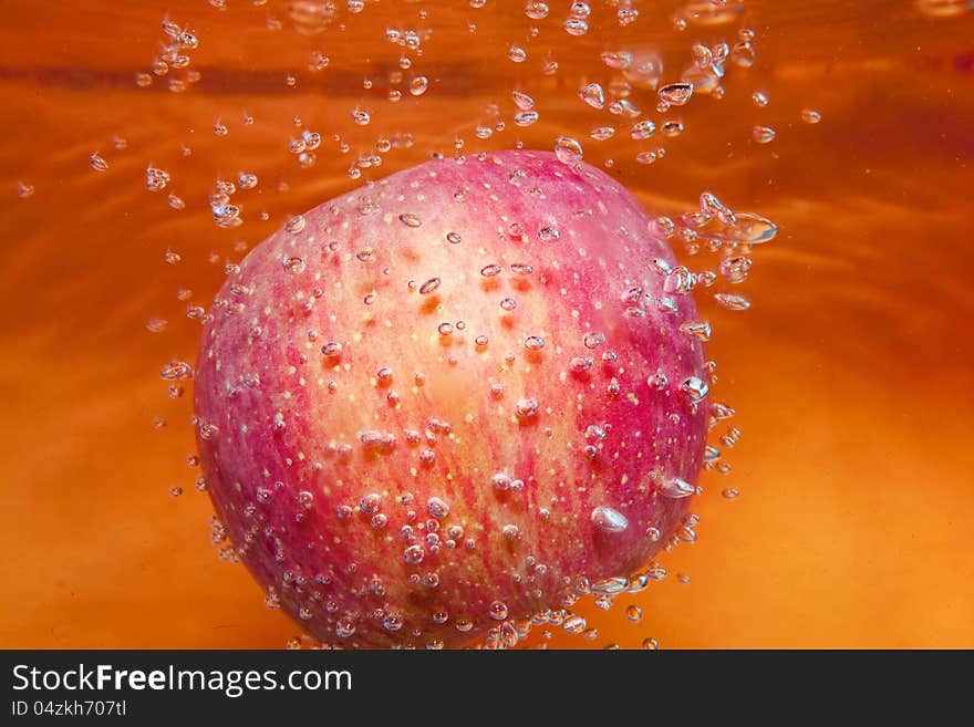 Red apple in water with bubbles