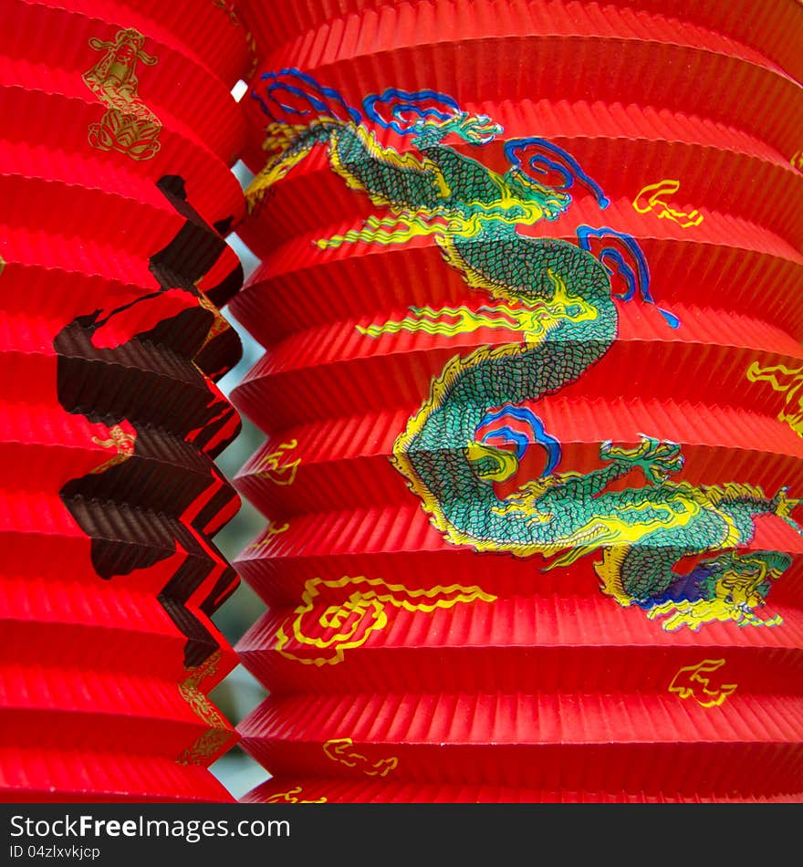 Closeup of two red Chinese paper lanterns illustrated with a dragon and calligraphy