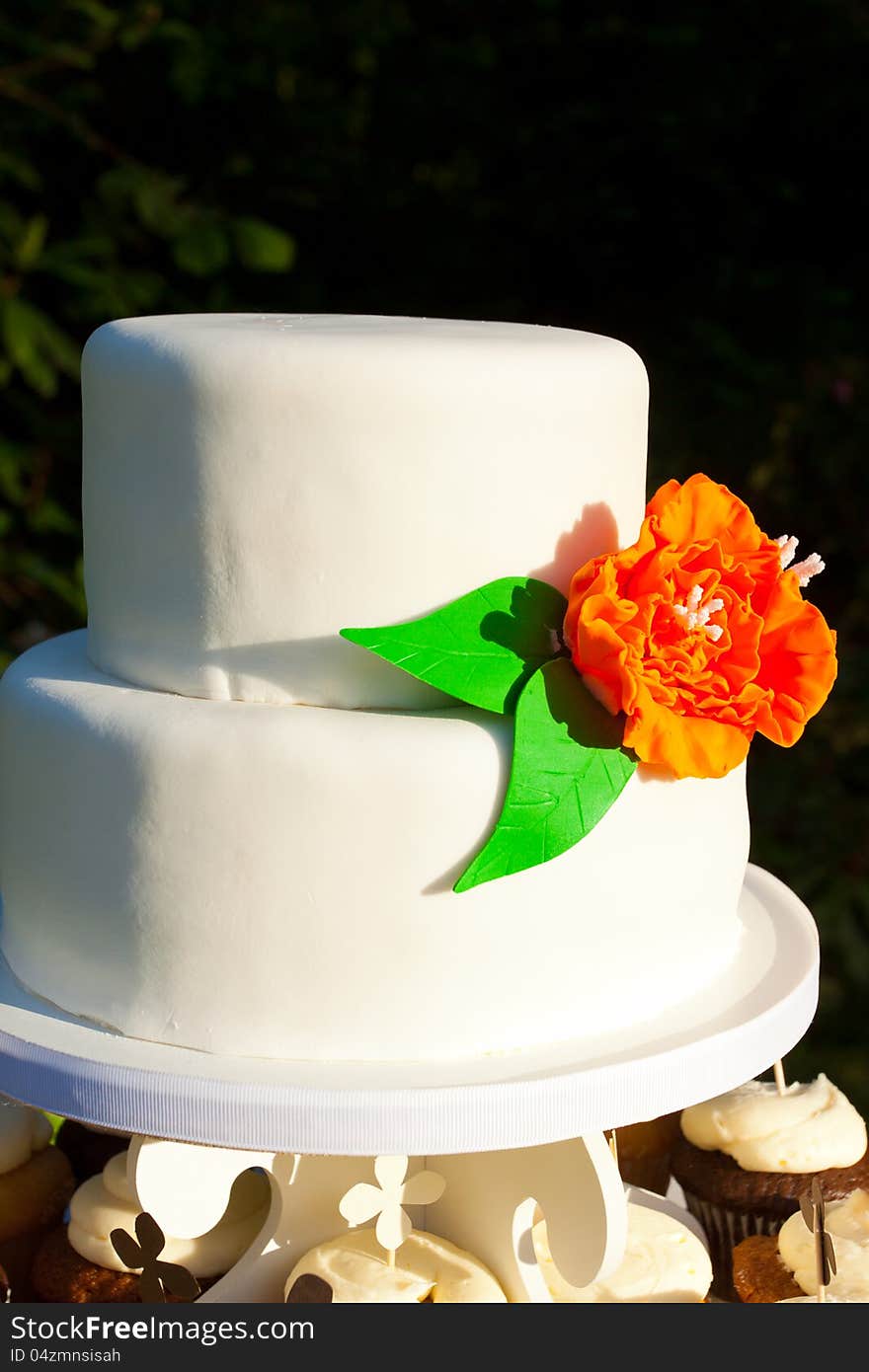 A simple wedding cake made of mostly white fondant and an orange and green flower. A simple wedding cake made of mostly white fondant and an orange and green flower.