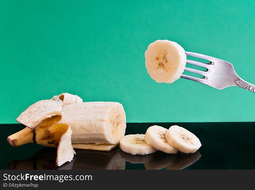 Half a banana and cut four pieces of one impaled on a fork on a black plate are. Half a banana and cut four pieces of one impaled on a fork on a black plate are