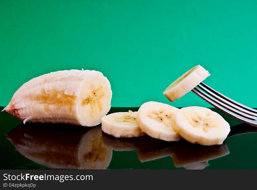 half a banana and cut four pieces of one impaled on a fork on a black plate are. half a banana and cut four pieces of one impaled on a fork on a black plate are