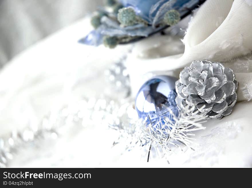 Silver pine cones and blue ornaments on white background