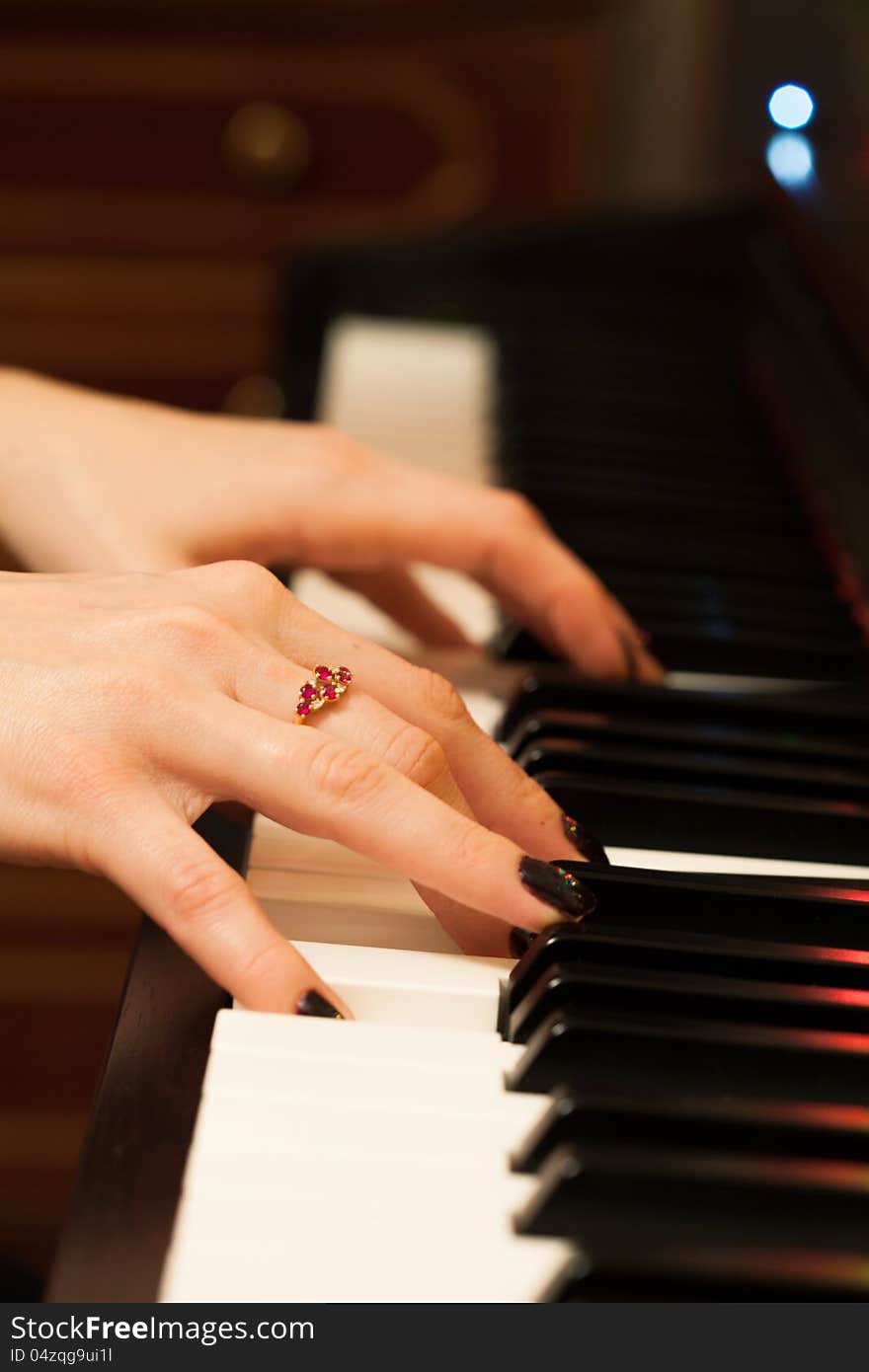 Girls hands playing the piano on dark background