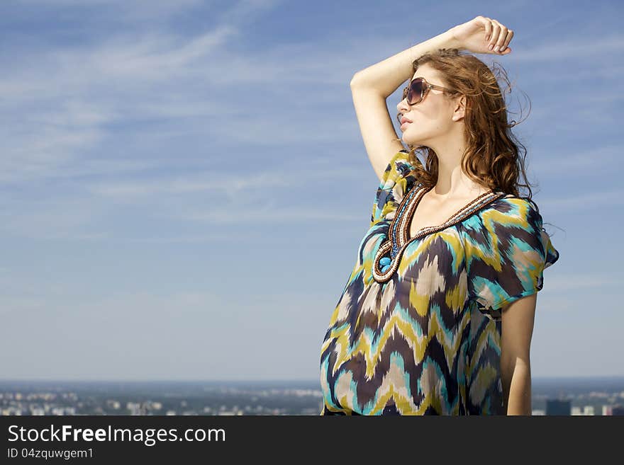 Portrait of beautiful brunette girl in sunglasses on background blue sky. Portrait of beautiful brunette girl in sunglasses on background blue sky