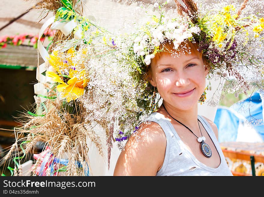 Young smiling woman with summer flowers wreath on head