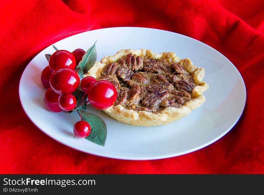 Christmas pecan tart decorated with artificial red cherries with a red fabric background. Christmas pecan tart decorated with artificial red cherries with a red fabric background.