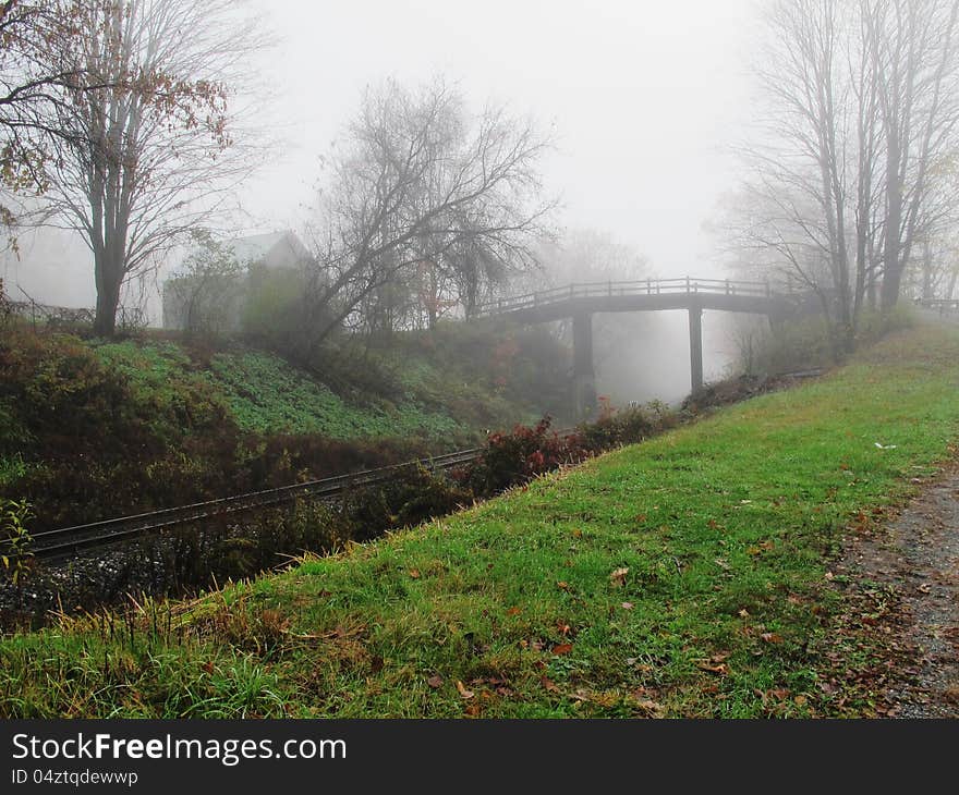 Bridge over train tracks with shed in the fog and light shining through the trees and fog. Dreamy. Bridge over train tracks with shed in the fog and light shining through the trees and fog. Dreamy