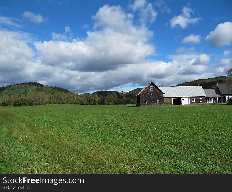 Big sky with white clouds and distant hills with farmhouse and green mowed lawn. Big sky with white clouds and distant hills with farmhouse and green mowed lawn.