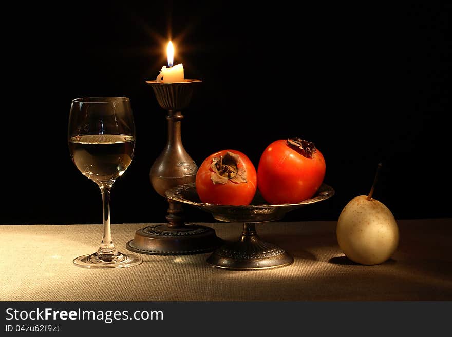 Vintage still life with fruits in bowl and wineglass near lighting candle. Vintage still life with fruits in bowl and wineglass near lighting candle