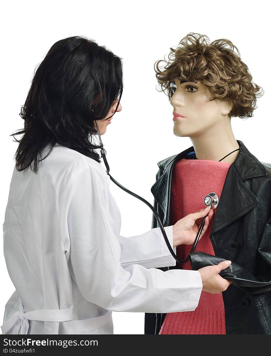 Young woman is examining the chest of the mannequin. She is wearing a white doctor's smock and using a stethoscope. Young woman is examining the chest of the mannequin. She is wearing a white doctor's smock and using a stethoscope.