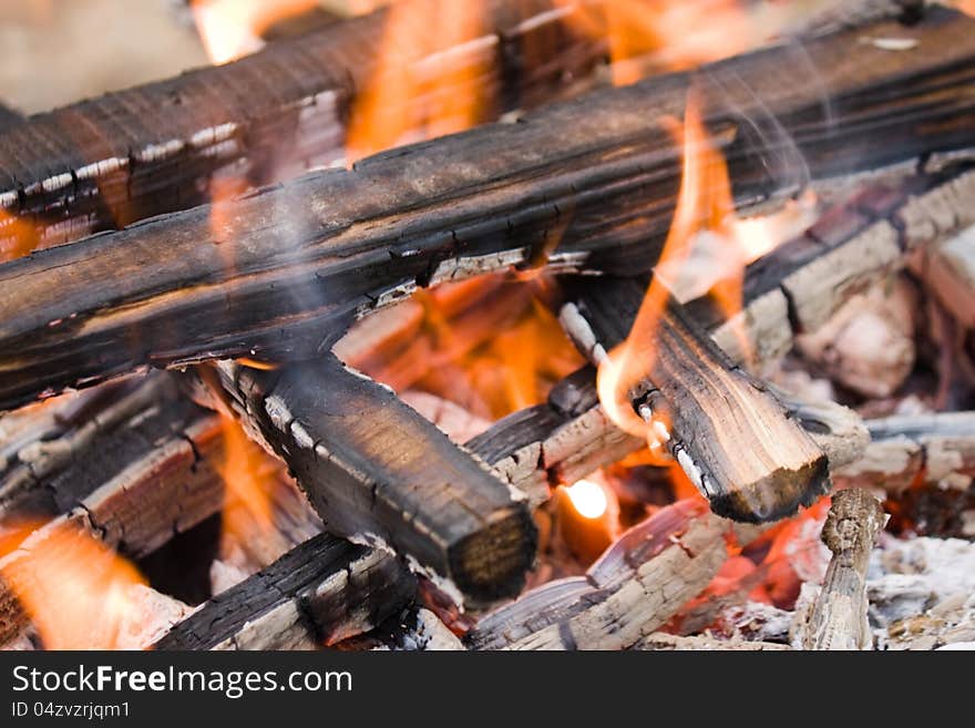 Camping bonfire with flame and firewood fragment close-up view. Camping bonfire with flame and firewood fragment close-up view