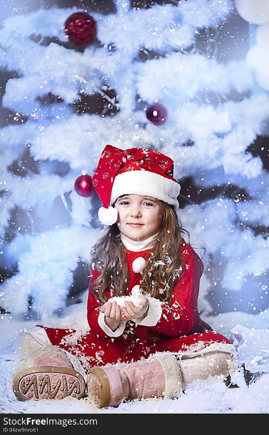 A little girl dressed as Santa Claus under the Christmas tree