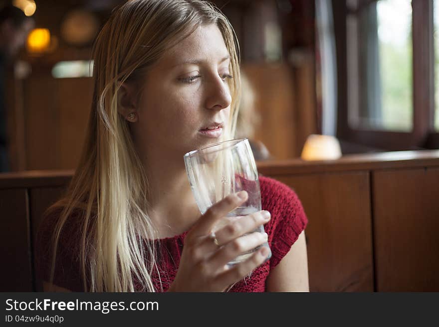 Young woman drinking water at a pub