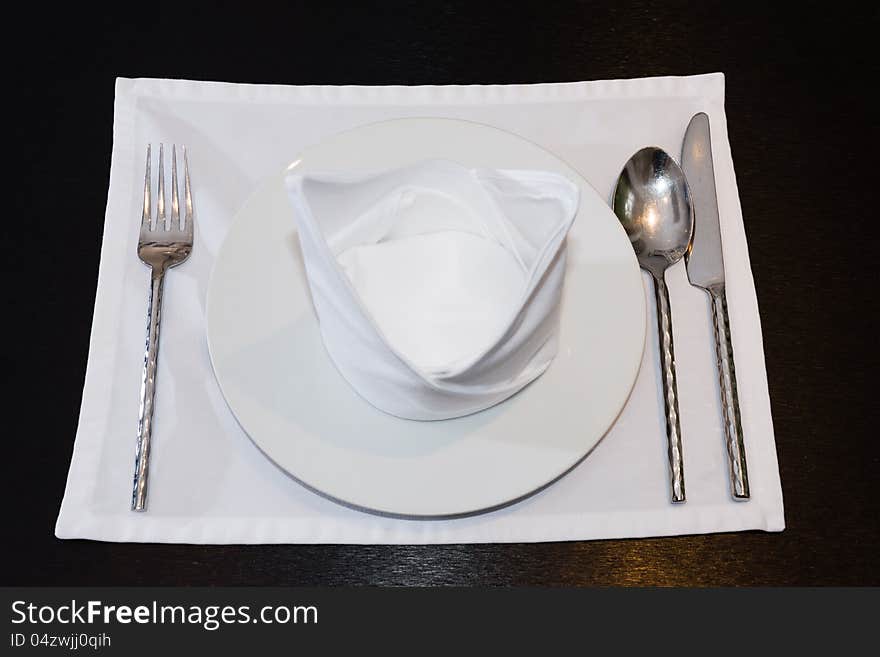 White napkins folded as triangles on plates with silverware set on the table