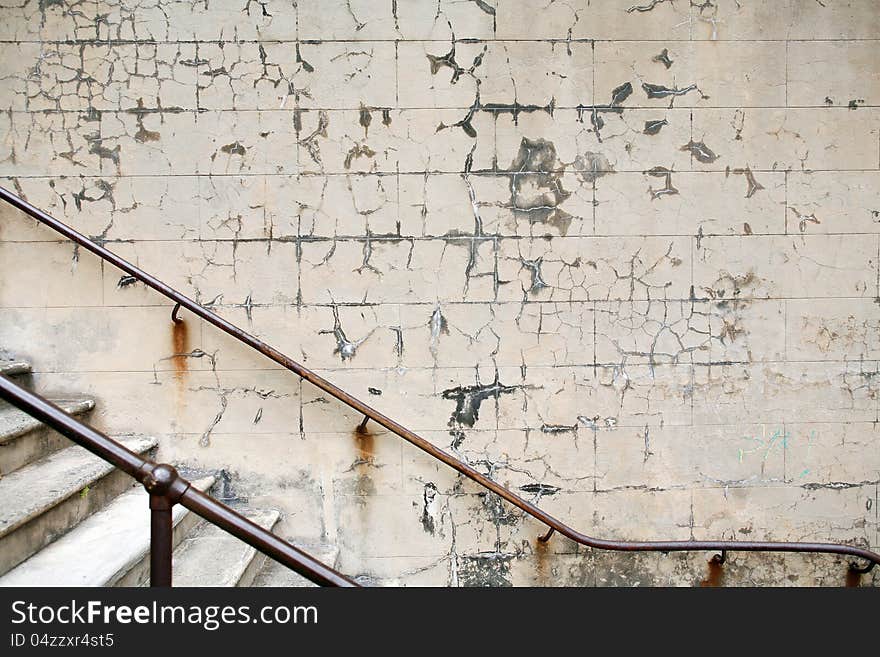 Detail of rusty handrail and wall with peeling paint in an old stairwell