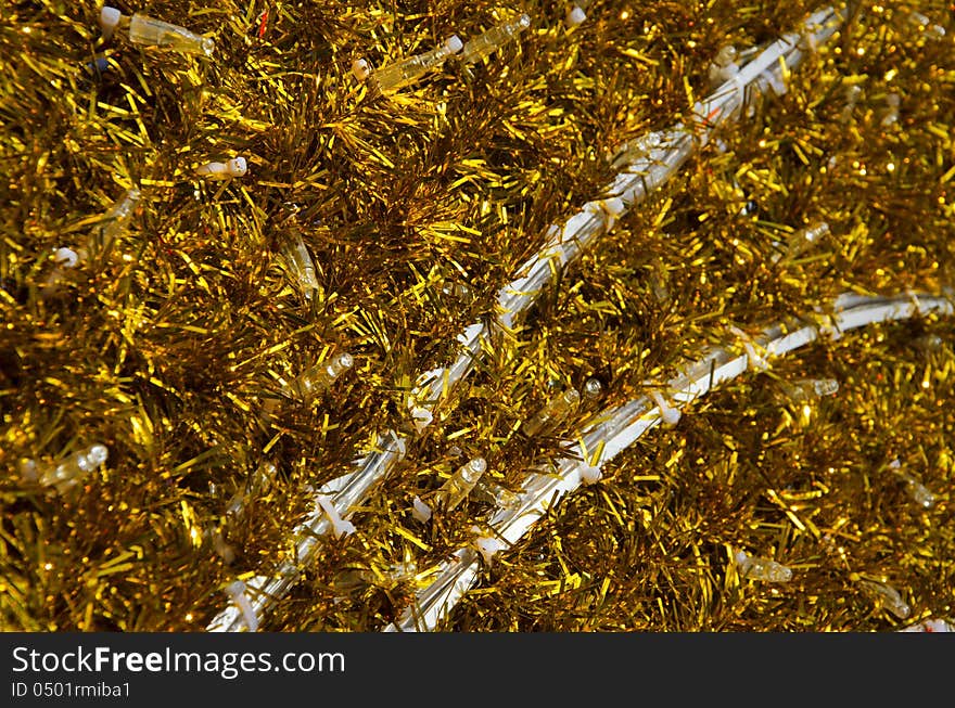 Yellow tinsel Christmas decoration background texture with white bulbs