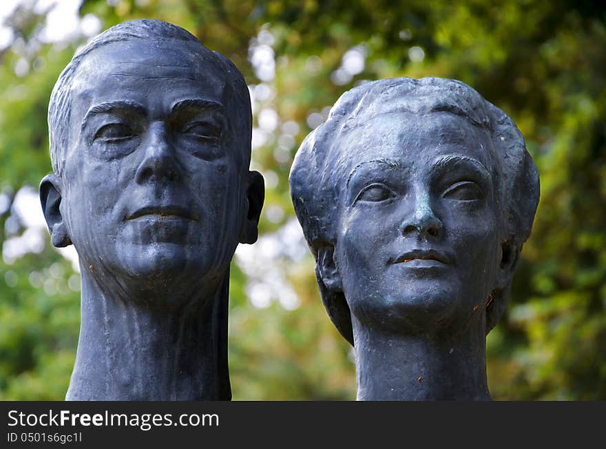 Bronze sculpture of a couple on a green vegetal background