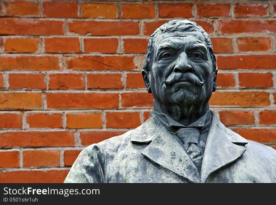 Sculpture of a serious man with moustache on a red bricks wall background. Sculpture of a serious man with moustache on a red bricks wall background