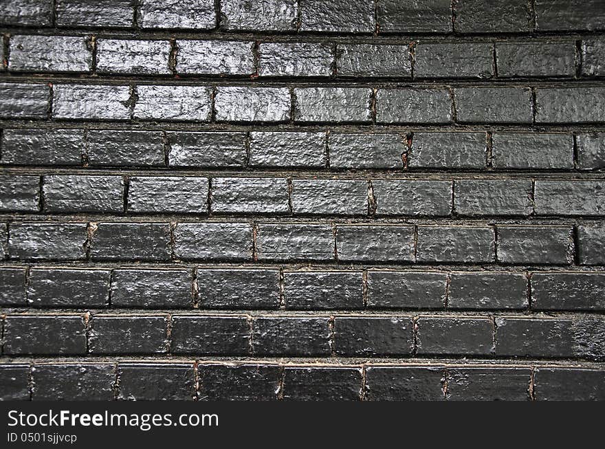 Black painted brick wall background with light reflections. Black painted brick wall background with light reflections