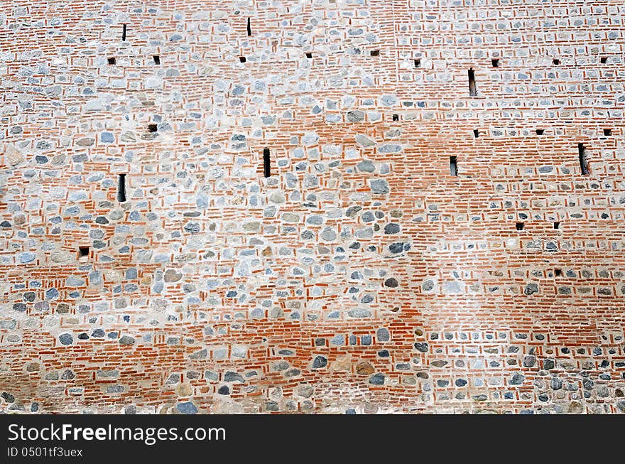 Crenels within a monastery wall built with stones and bricks. Crenels within a monastery wall built with stones and bricks