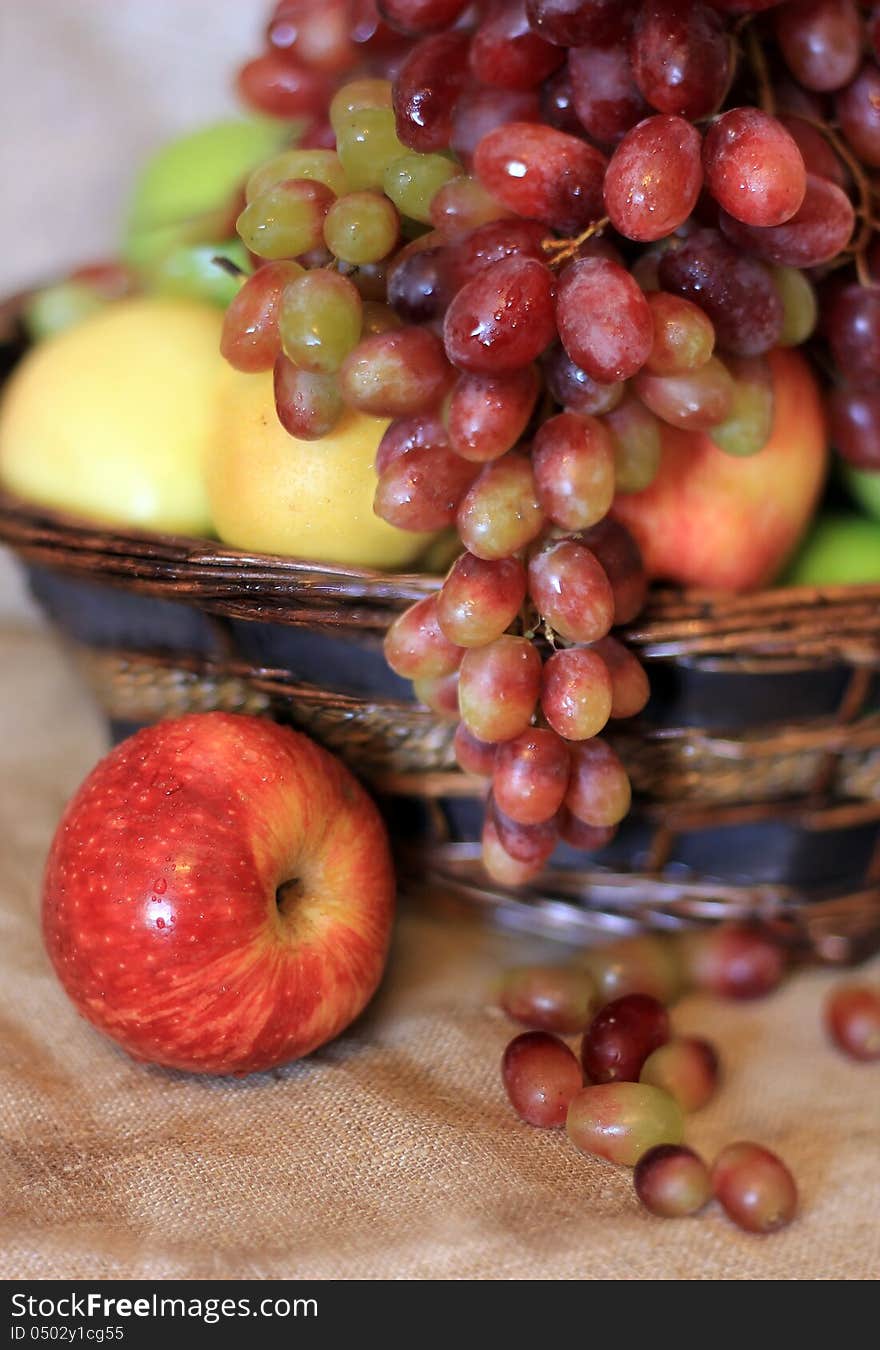 Fresh fruits with water drops in the basket on the tablecloth from canvas. Fresh fruits with water drops in the basket on the tablecloth from canvas