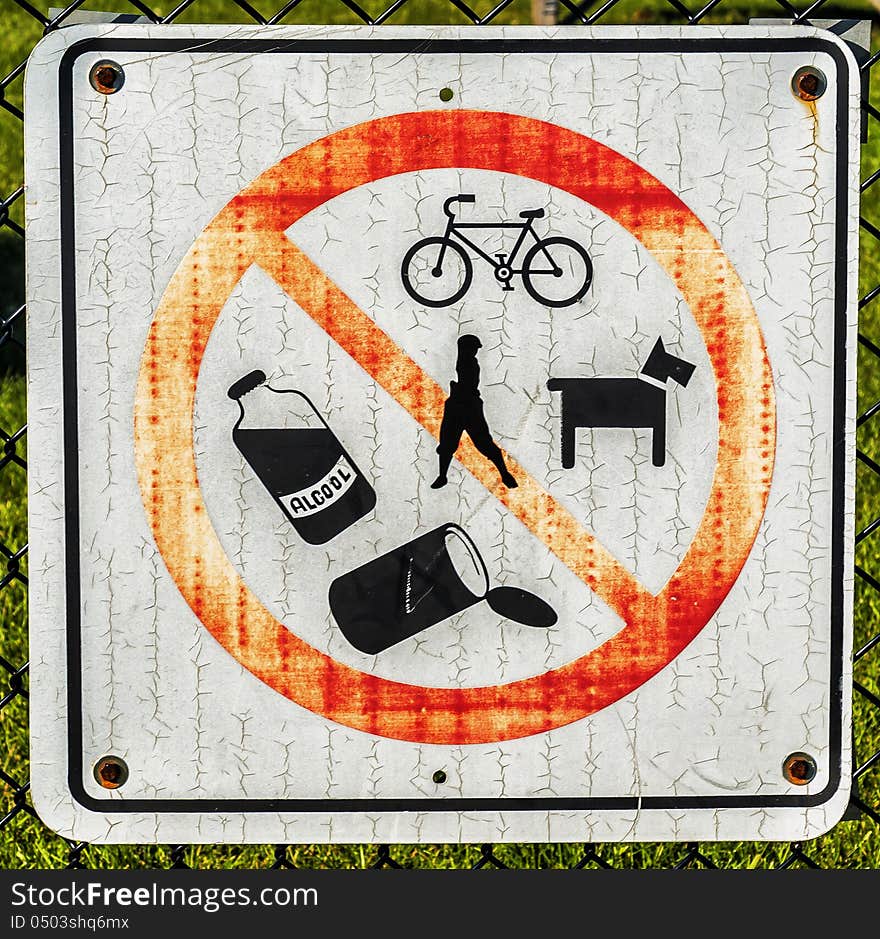 No bicycles, no golfing, no dogs, no alcool, no cans sign on a fence park. No bicycles, no golfing, no dogs, no alcool, no cans sign on a fence park