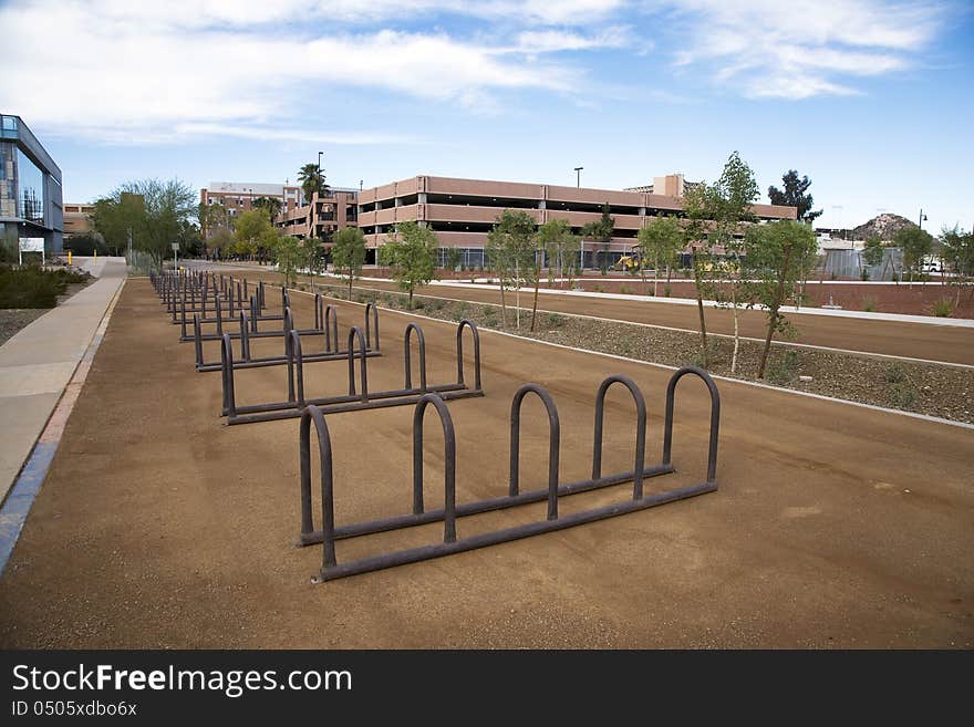 Empty Row of bike racks adjacent to light rail and campus