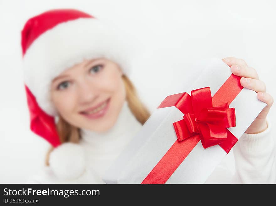 Happy young woman holds out a Christmas present, white gift with a red ribbon. Happy young woman holds out a Christmas present, white gift with a red ribbon