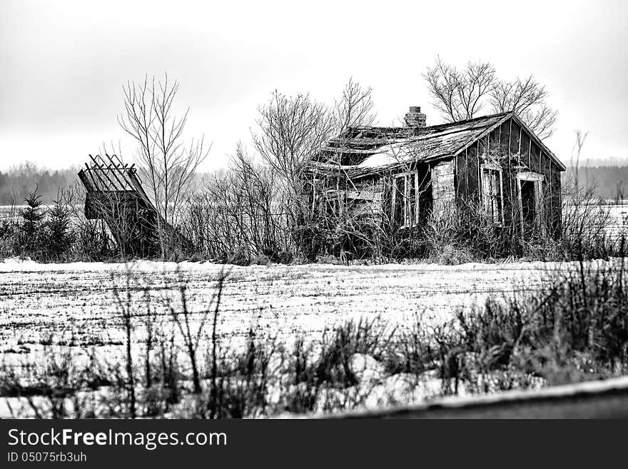 An old decaying shack on farm land in black and white.