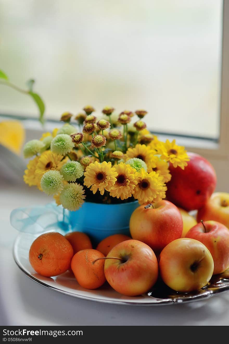 On a white background ripe apples, mandarin bright bouquet of autumn flowers in the window. On a white background ripe apples, mandarin bright bouquet of autumn flowers in the window