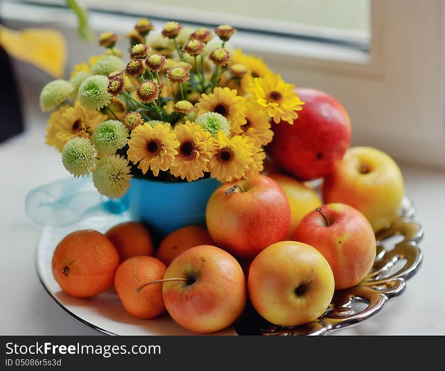 On a white background ripe apples, mandarin bright bouquet of autumn flowers in the window. On a white background ripe apples, mandarin bright bouquet of autumn flowers in the window