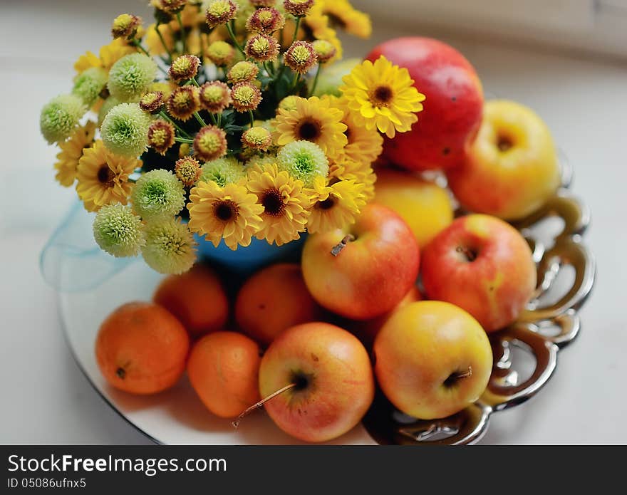 On a white background ripe apples, mandarin bright bouquet of autumn flowers in the window. On a white background ripe apples, mandarin bright bouquet of autumn flowers in the window