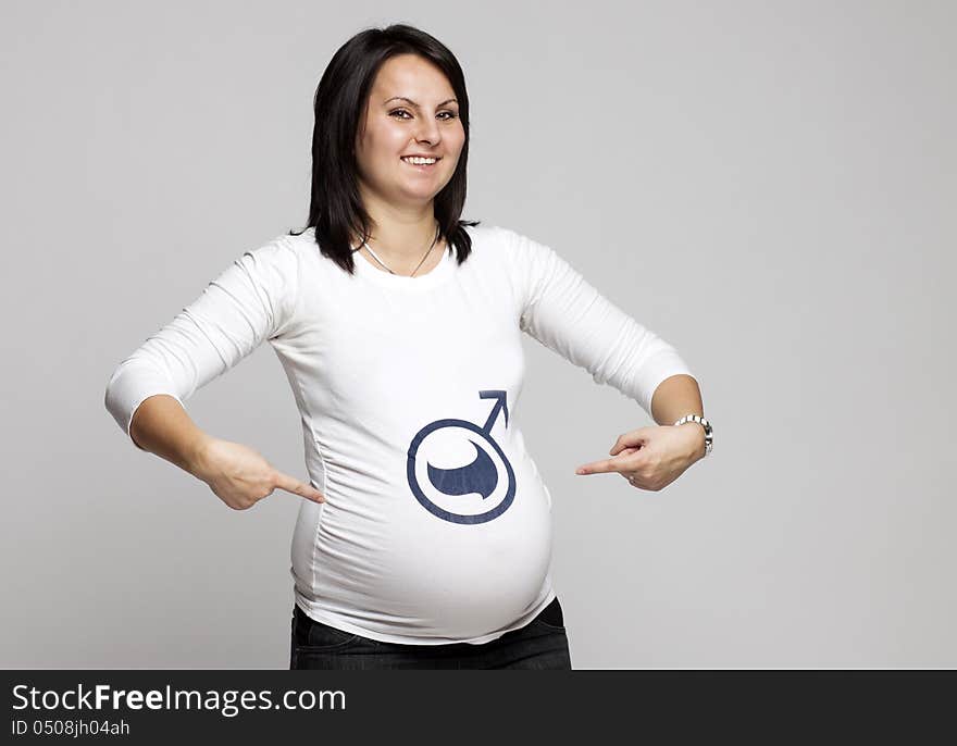 Pregnant woman pointing to boy sign on her shirt. Pregnant woman pointing to boy sign on her shirt