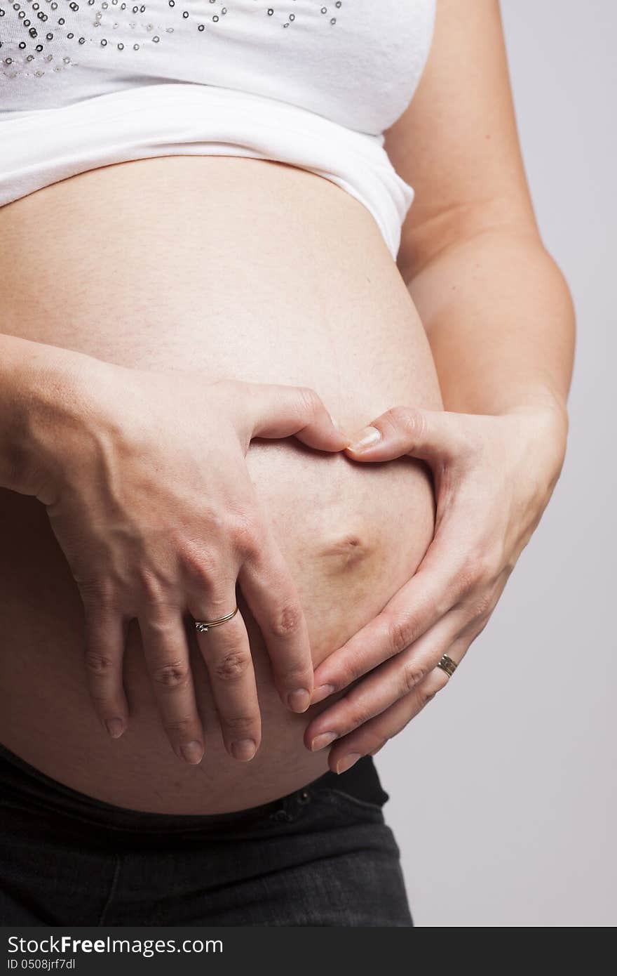 Hands of a pregnant woman making a heart with hands on her belly. Hands of a pregnant woman making a heart with hands on her belly