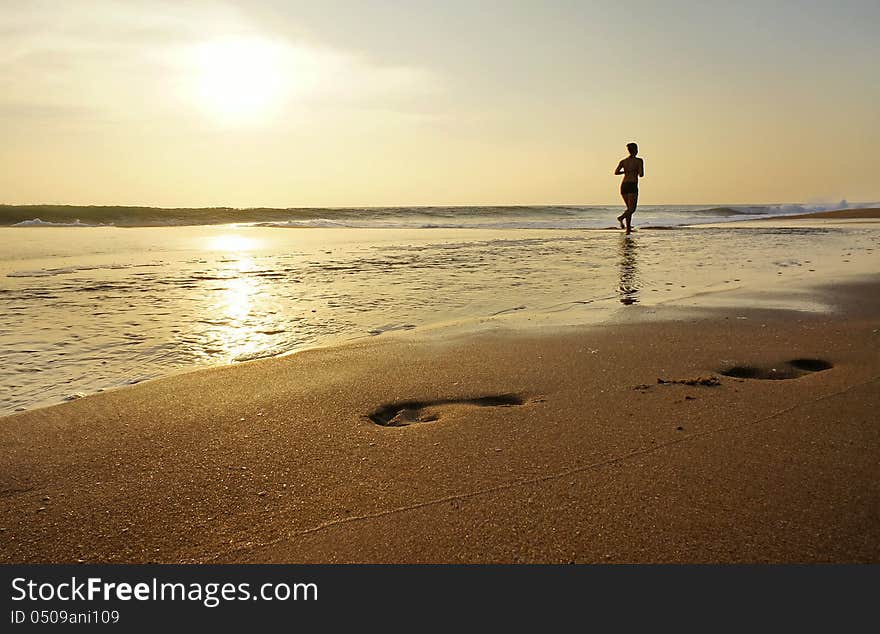 Woman Jogging Along The Edge Of The Ocean.