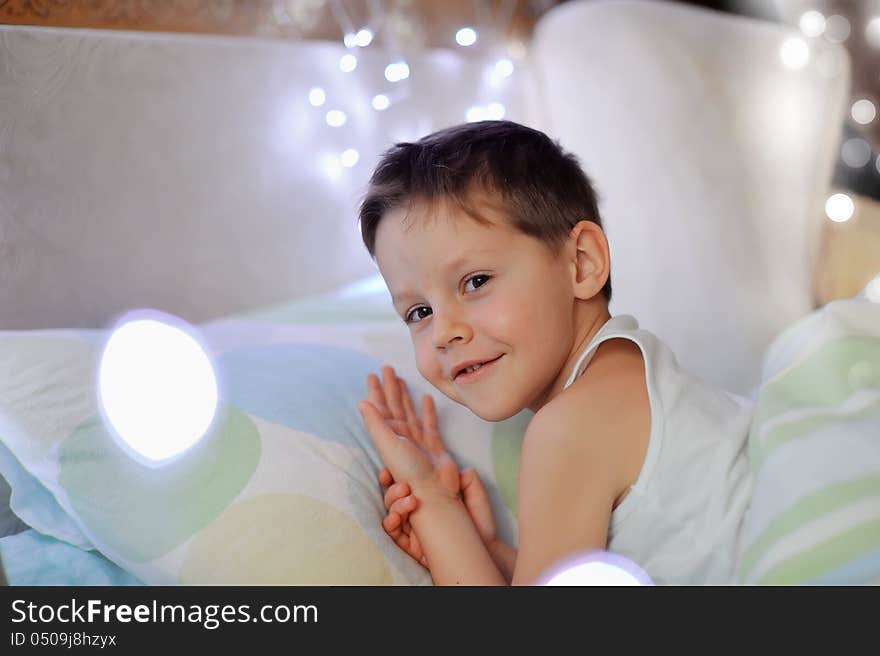 The little boy woke up in a children's cozy bed of lights. The little boy woke up in a children's cozy bed of lights