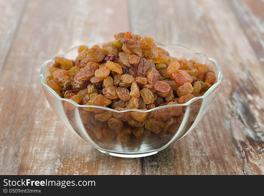 Glass bowl with sultana raisins closeup on wooden table