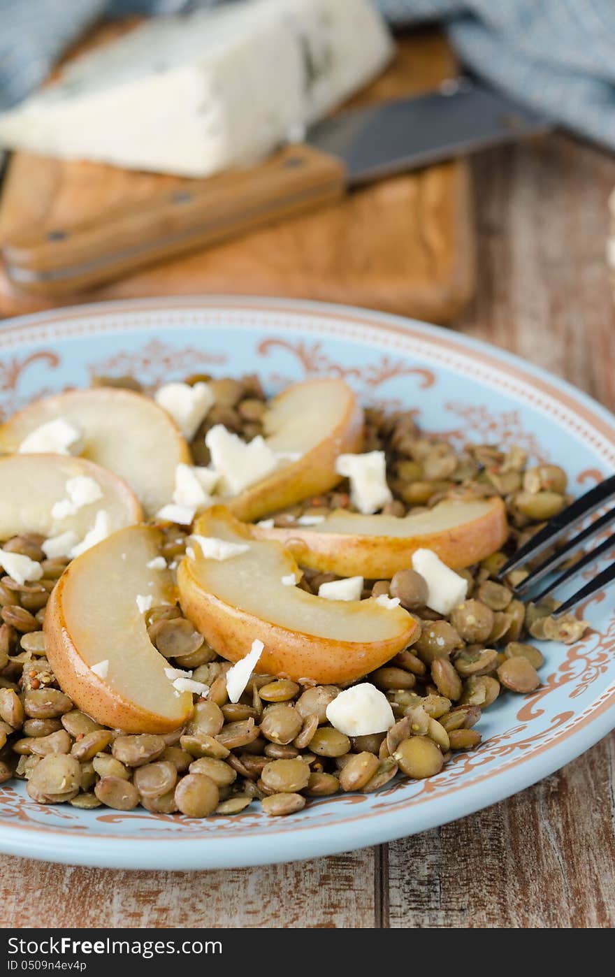 Lentil salad with caramelized pears and Roquefort cheese on a blue plate, closeup. Lentil salad with caramelized pears and Roquefort cheese on a blue plate, closeup