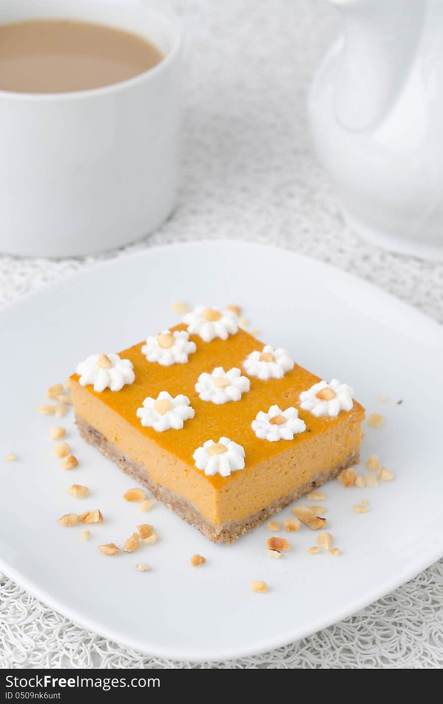 Pumpkin cake, decorated with flowers made of whipped cream and nuts on a plate