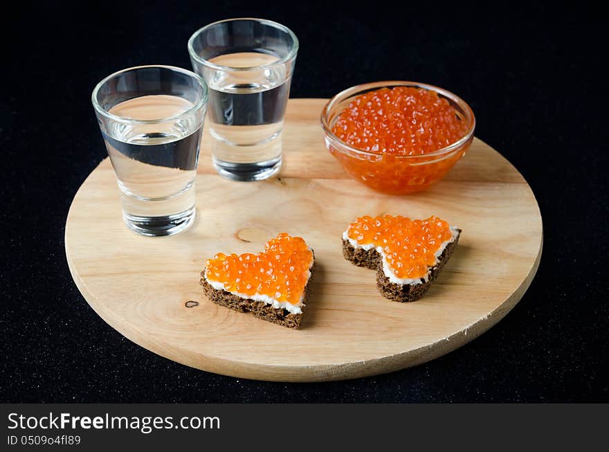 Two sandwich with red caviar in the form of a heart  and vodka