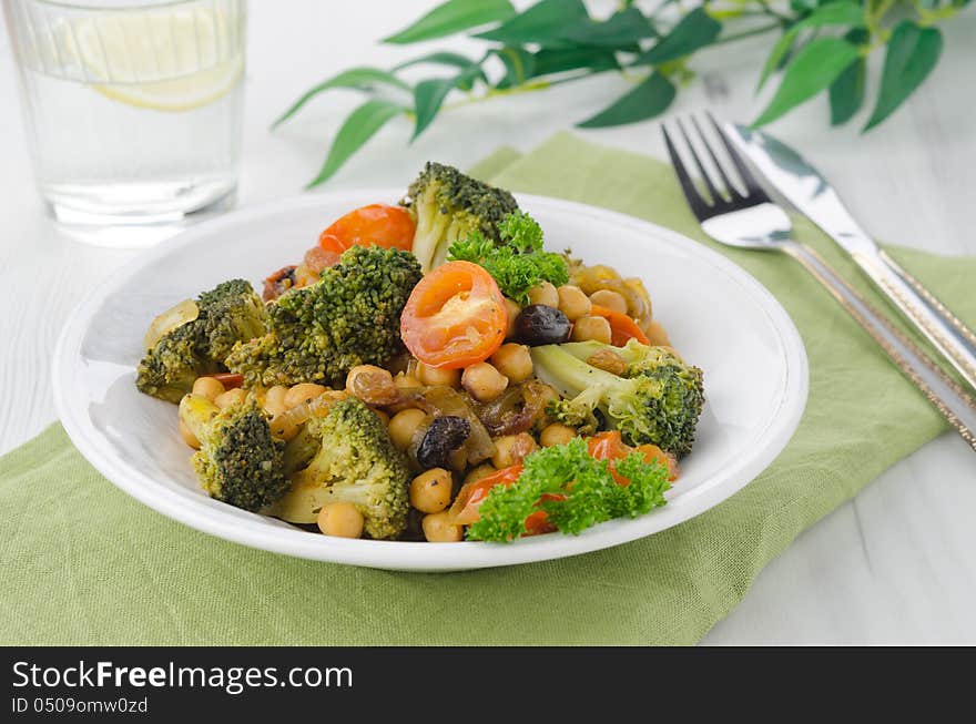 Warm salad with chickpeas, broccoli and raisins on the plate, horizontal