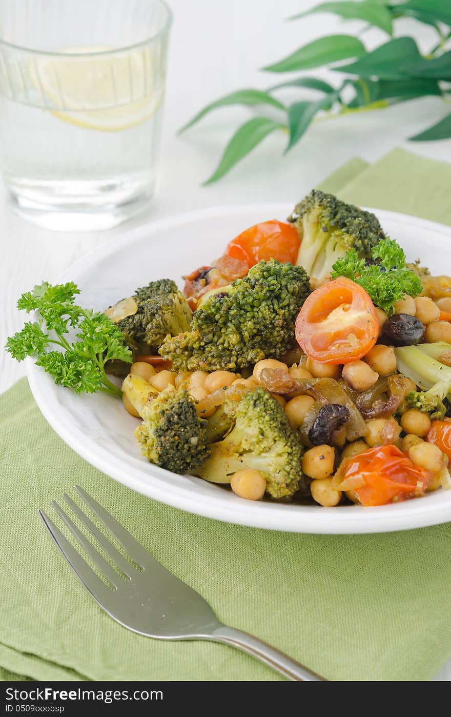 Warm salad with chickpeas, broccoli, raisins on a plate, closeup. Warm salad with chickpeas, broccoli, raisins on a plate, closeup