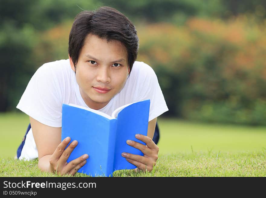 Young man open a book, look to the camera in outdoor